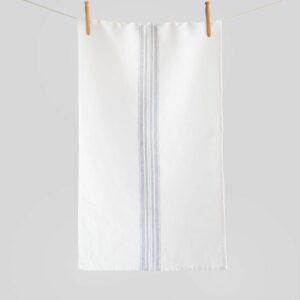 Crisp white linen tea towel with grey center stripes hanging from a clothesline wit two wooden pegs