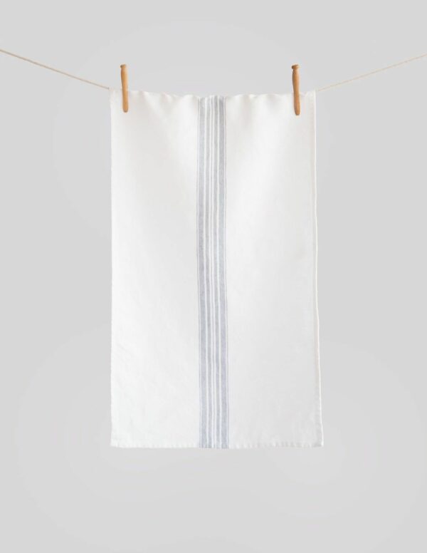 Crisp white linen tea towel with grey center stripes hanging from a clothesline wit two wooden pegs
