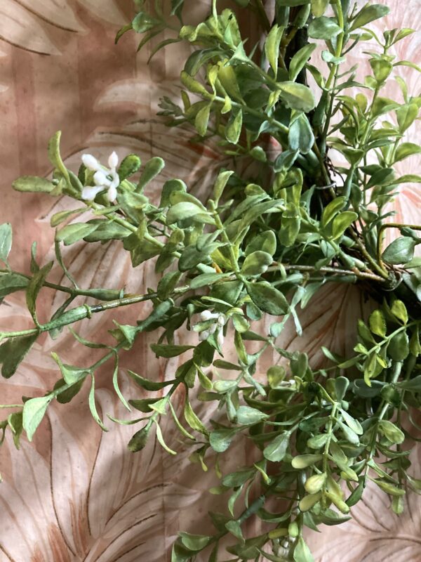 Detail of realistic artificial boxwood wreath to show subtle colour variations in the leaves.