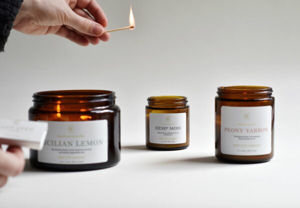 East City Candles Hemp Moss, Sicilian Lemon, and Peony Yarrow Candles in amber glass jars.
