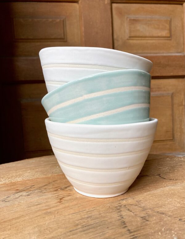 A stack of three pottery bowls in off-white and vintage blue.