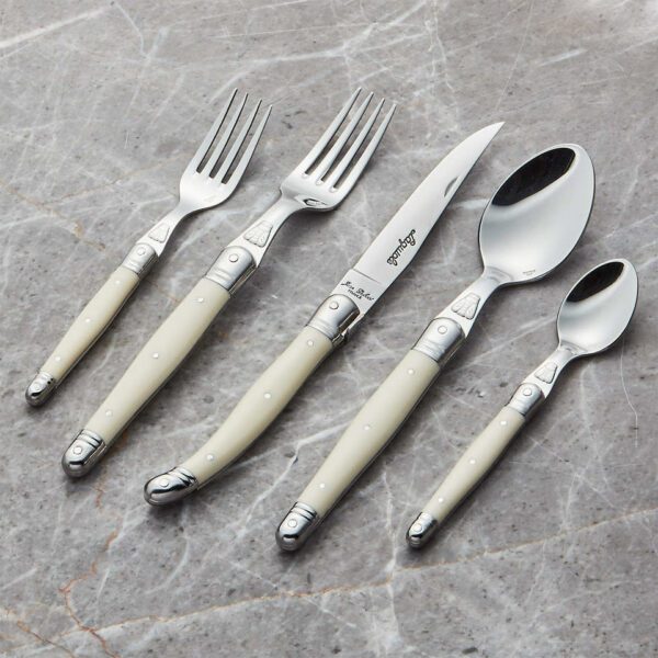 A set of five pieces of cutlery is displayed on a marble surface. The set includes a dinner fork, a salad fork, a knife, a tablespoon, and a teaspoon. Each piece features a polished stainless steel head and a smooth, cream-colored handle with decorative silver accents. The cutlery is arranged in a line, showcasing its elegant design and craftsmanship.