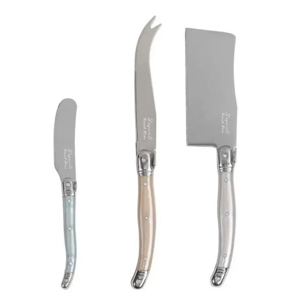 Three cheese knives are displayed, each with a distinct design. On the left, a small spreader with a light blue handle. In the center, a curved knife with a beige handle, designed for slicing. On the right, a larger, rectangular blade with a silver handle, suitable for cutting. All knives feature polished stainless steel blades and decorative detailing on the handles.