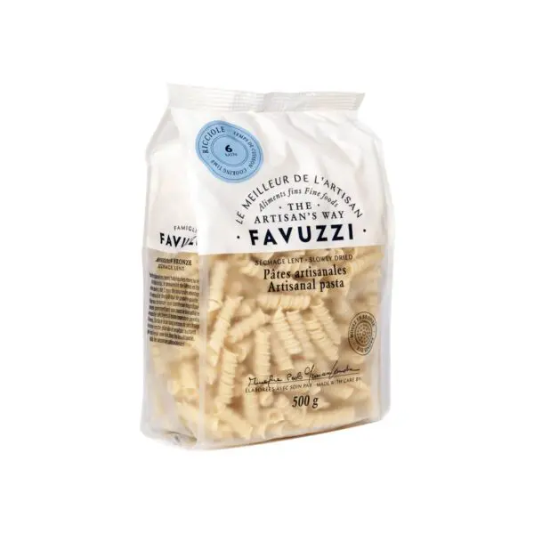 A clear plastic bag filled with artisanal pasta is displayed. The pasta is shaped in a twisted, ridged design and is light beige in color. The bag features a label with the brand name "Favuzzi" prominently at the top, along with the text "The Artisan's Way." Additional details include "Pâtes artisanales" and "500 g," indicating the weight. The packaging also includes information about the pasta being slowly dried and made with care.