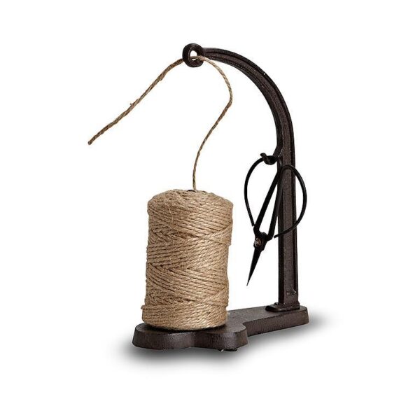 A vintage-style thread holder features a spool of natural twine secured on a sturdy, dark metal base. The holder has a curved arm that supports the spool, with a length of twine extending from it. A pair of scissors is attached to the side of the holder, adding a practical touch to the design. The overall aesthetic is rustic and functional, suitable for crafting or decorative purposes.