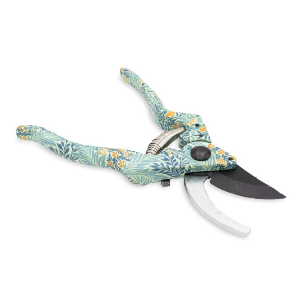 A pair of pruning shears with a decorative floral pattern on the handles. The handles are predominantly light blue with green leaves and small orange flowers. The shears feature a curved blade made of metal, with one side being serrated and the other smooth. A spring mechanism is visible between the handles, and there is a black button on one side for locking or unlocking the shears. The background is plain white, emphasizing the design of the tool.
