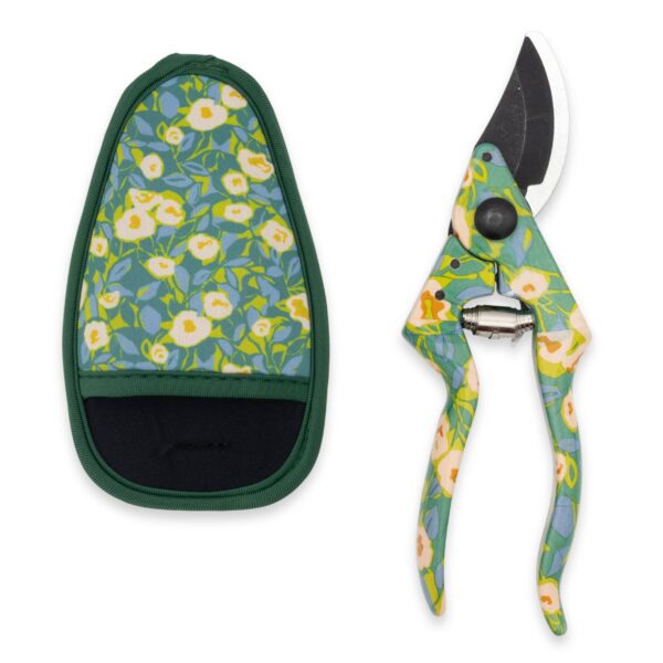A pair of garden pruners is displayed alongside a protective sheath. The pruners feature a floral design with green, yellow, and blue colors, while the sheath has a similar floral pattern on a light blue background, bordered in green. The pruners have a curved blade and a spring mechanism, indicating they are designed for cutting plants and branches.