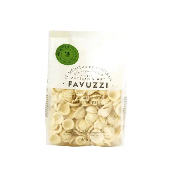 A clear plastic bag filled with orecchiette pasta, featuring a light beige color. The packaging includes a label with the brand name "Favuzzi" and the phrase "The Artisan's Way." It indicates that the pasta is artisanal and slow-dried, with a cooking time of 18 minutes. The bag contains 500 grams of pasta. The design is simple and elegant, emphasizing the artisanal quality of the product.