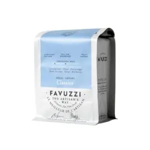A bag of ground coffee labeled "Classico" from Favuzzi. The packaging features a predominantly white design with a light blue top section. It indicates that the coffee is an espresso roast, weighing 340 grams (12 oz). Descriptive notes highlight flavors such as dark chocolate, floral, and red berries. The bag also includes the phrase "The Artisan's Way" and mentions that it is slow roasted.