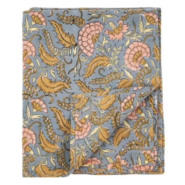 A folded fabric featuring a floral pattern with intricate designs. The background is a soft blue, adorned with large pink and yellow flowers, along with green leaves and swirling vines. The edges are neatly stitched, and one corner is slightly unfolded, revealing more of the pattern. The overall look is vibrant and decorative, suitable for home decor or crafting projects.