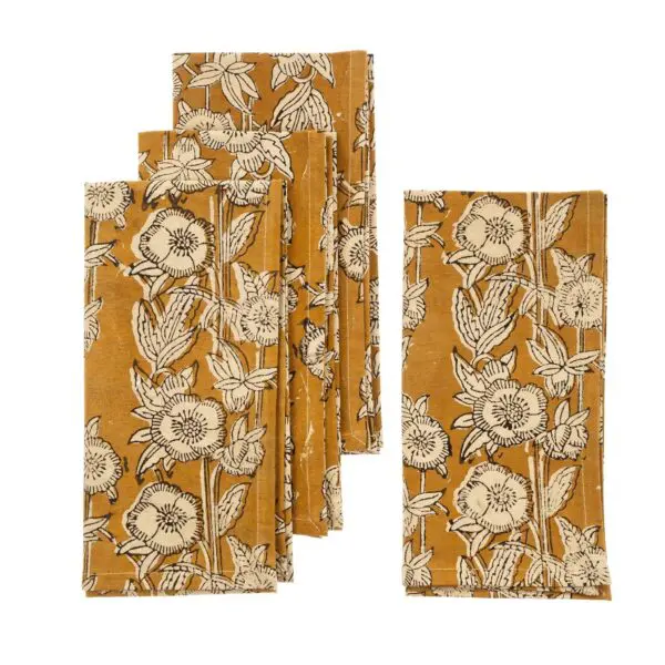 A collection of fabric napkins featuring a floral pattern. The background is a warm mustard yellow, adorned with intricate black and white illustrations of flowers and leaves. There are five napkins in total, arranged in a slightly overlapping manner, showcasing the design prominently.