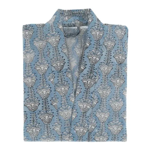 A folded garment featuring a light blue fabric adorned with a repeating floral pattern in black. The design consists of stylized flowers and leaves arranged vertically. The collar is open, showcasing the interior of the garment. The overall look is elegant and suitable for casual or semi-formal wear.